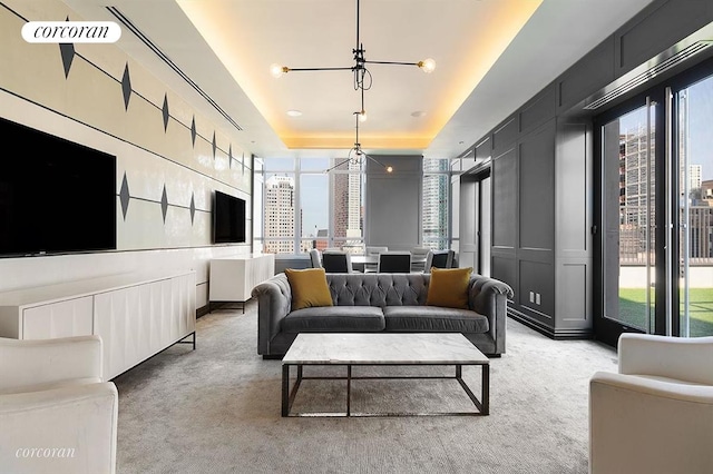 living area featuring a raised ceiling, an inviting chandelier, light carpet, and a decorative wall