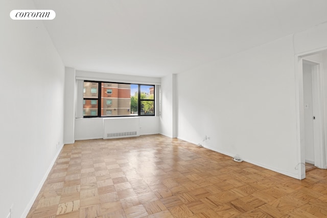 unfurnished room with visible vents, baseboards, and radiator heating unit