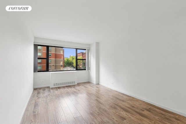 empty room featuring baseboards, wood finished floors, and visible vents