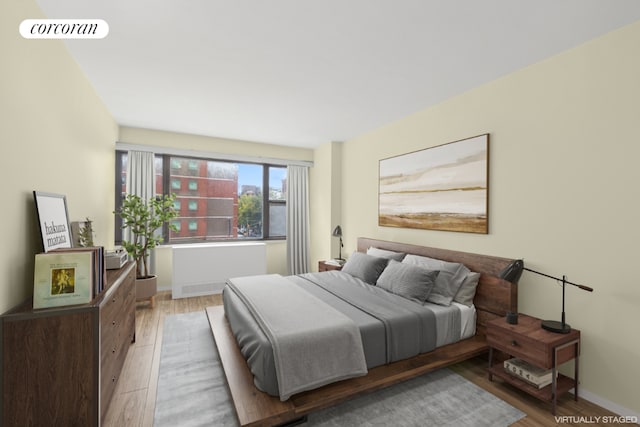 bedroom with baseboards, visible vents, light wood-style flooring, and radiator heating unit