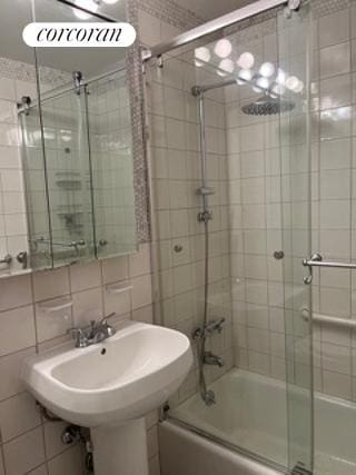 bathroom with enclosed tub / shower combo, backsplash, and tile walls