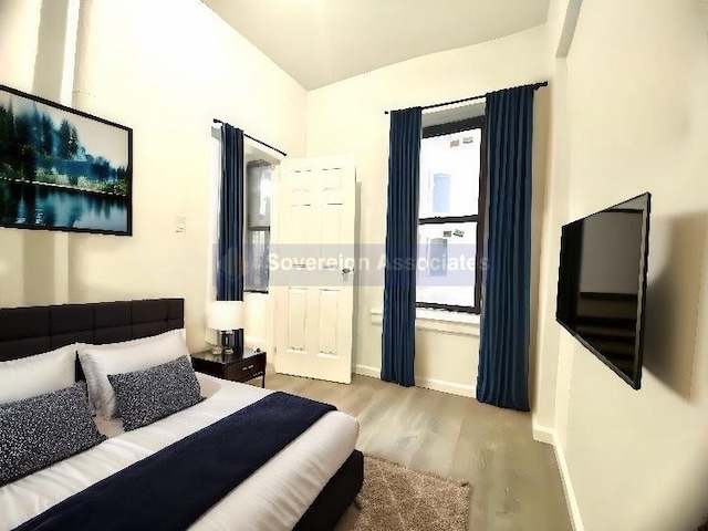 bedroom with hardwood / wood-style floors and vaulted ceiling