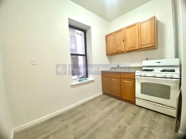 kitchen featuring sink, light hardwood / wood-style floors, and white gas range oven