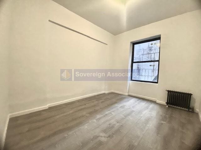 empty room with radiator heating unit and dark hardwood / wood-style floors