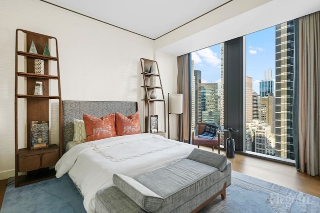 bedroom featuring expansive windows and hardwood / wood-style flooring