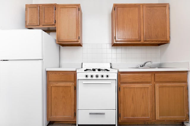 kitchen featuring white appliances, tasteful backsplash, light countertops, and a sink