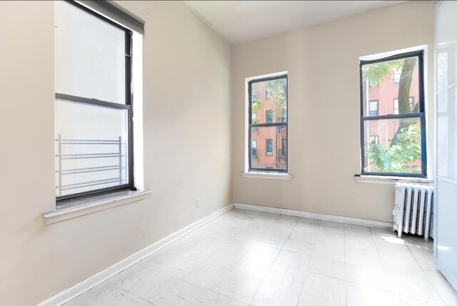 unfurnished room with baseboards and radiator