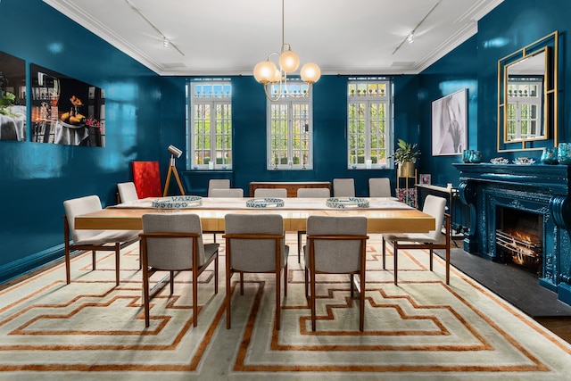 dining space featuring a lit fireplace, rail lighting, a wealth of natural light, and crown molding