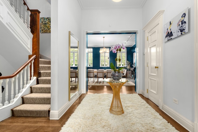 entryway featuring crown molding, a notable chandelier, dark wood finished floors, stairway, and baseboards