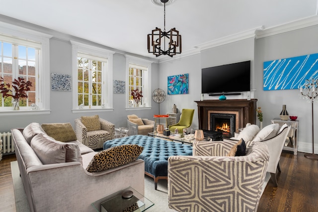 interior space featuring a warm lit fireplace, a notable chandelier, wood finished floors, baseboards, and crown molding