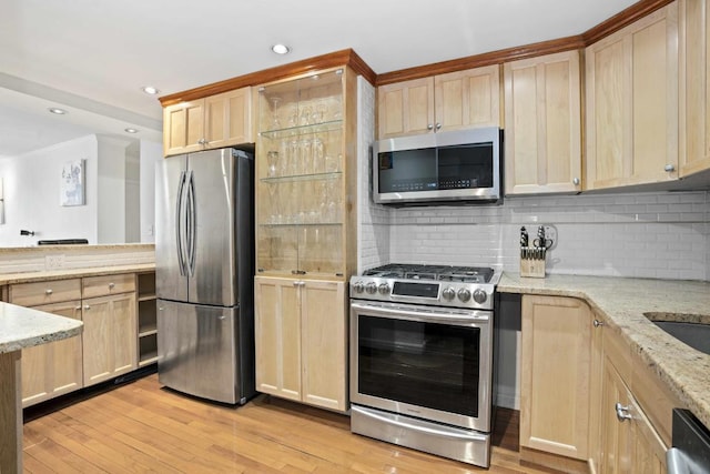 kitchen featuring backsplash, light stone countertops, light brown cabinets, and stainless steel appliances