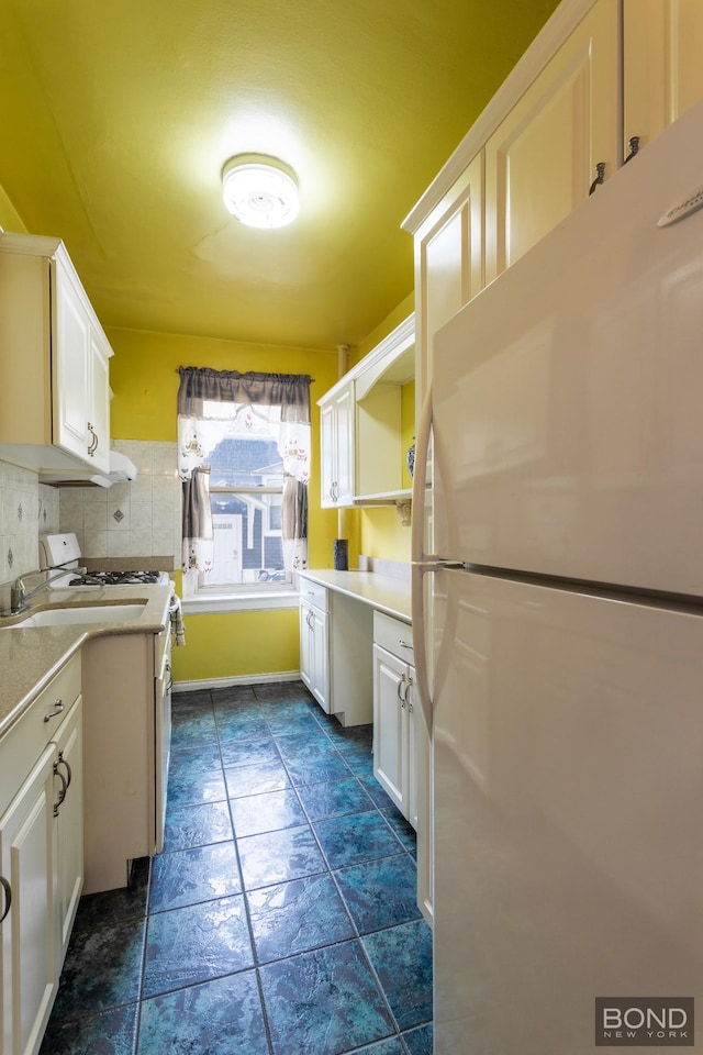 kitchen featuring built in desk, light countertops, decorative backsplash, white cabinets, and white appliances