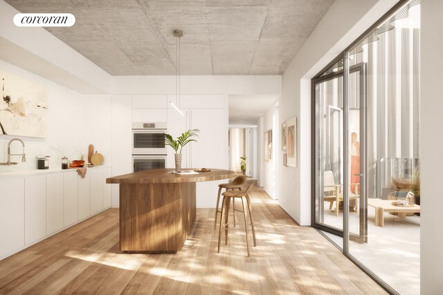 bar featuring wood counters, white cabinetry, white double oven, hanging light fixtures, and light hardwood / wood-style flooring