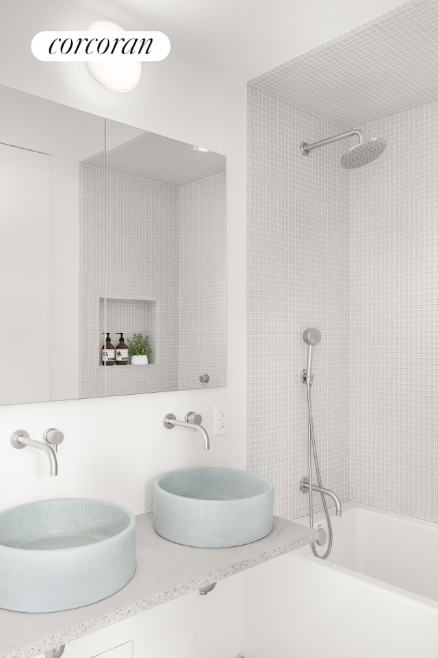 bathroom with shower / bath combination, a sink, and double vanity