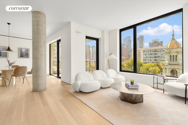 sitting room with a view of city, visible vents, ornate columns, and wood finished floors