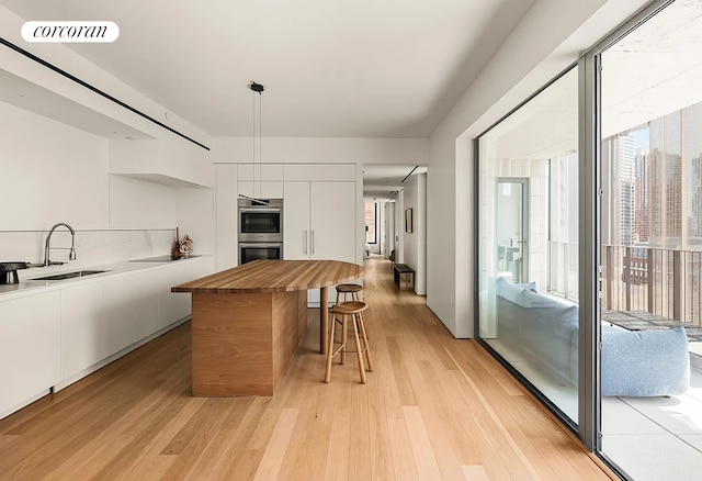 9 Chapel St Phb, Phb, New York City, NY 11201 - kitchen featuring modern cabinets, a sink, white cabinets, a kitchen breakfast bar, and light wood-style floors
