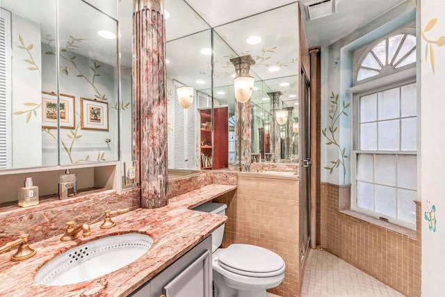 bathroom with tile walls, vanity, a shower, and toilet