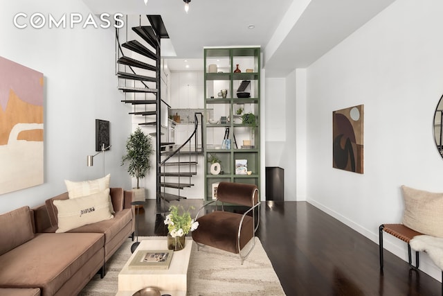 living area featuring baseboards, wood finished floors, and stairs