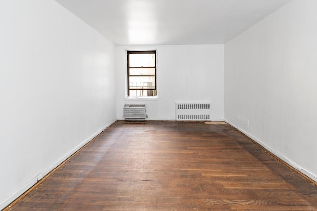 spare room featuring radiator heating unit and dark hardwood / wood-style floors