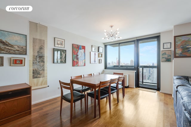 dining room with baseboards, visible vents, a view of city, a notable chandelier, and light wood-type flooring