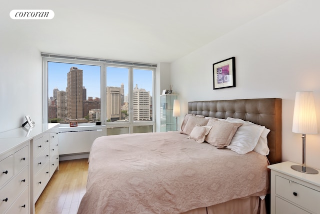 bedroom with a wall of windows and light hardwood / wood-style flooring