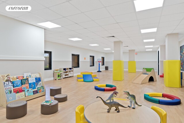 playroom with baseboards, visible vents, a drop ceiling, and wood finished floors