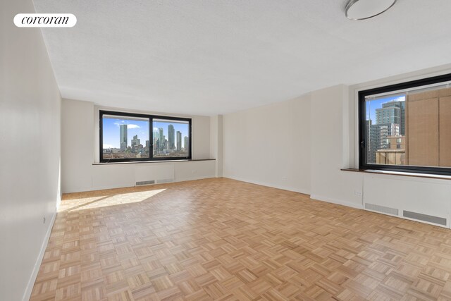 unfurnished room with baseboards, a view of city, and visible vents