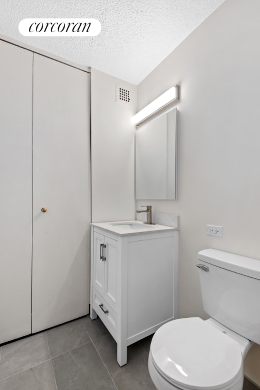 bathroom with a textured ceiling, tile patterned flooring, toilet, visible vents, and vanity