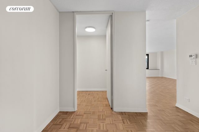 hallway with a textured ceiling, visible vents, and baseboards