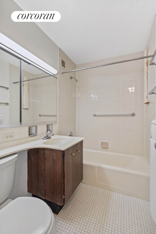 full bathroom featuring toilet, tiled shower / bath, tile patterned flooring, vanity, and a textured ceiling