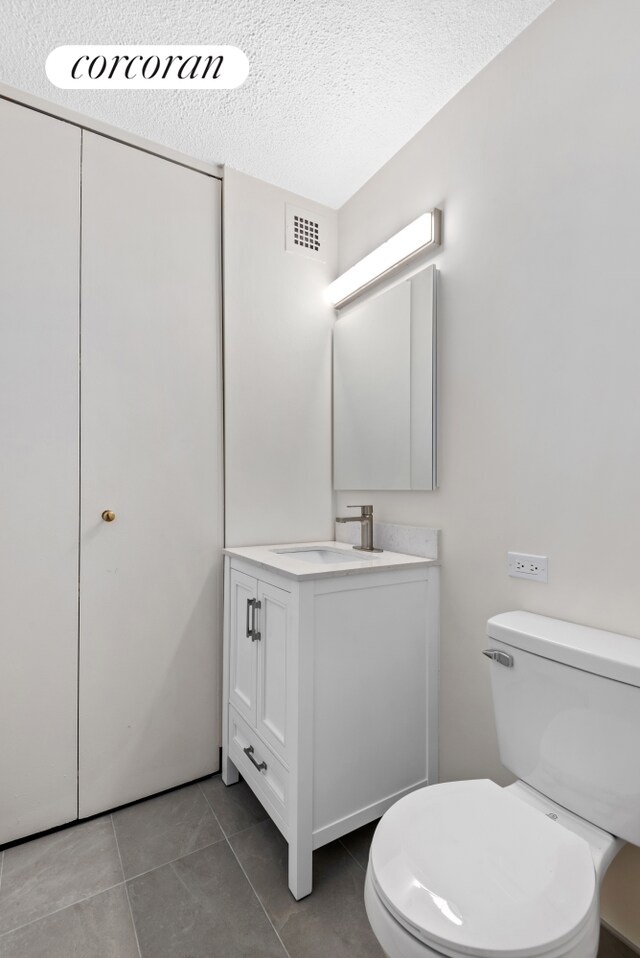 bathroom featuring visible vents, toilet, vanity, a textured ceiling, and tile patterned flooring