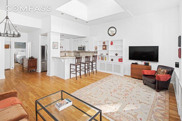 living room with light hardwood / wood-style flooring, a towering ceiling, and an inviting chandelier