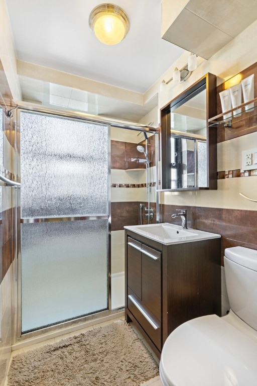 bathroom featuring a shower with shower door, vanity, and toilet