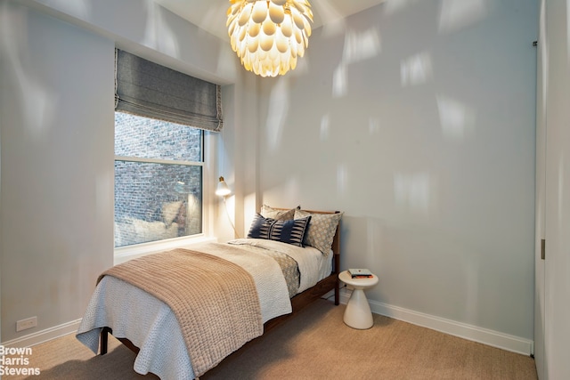 carpeted bedroom featuring a notable chandelier and baseboards