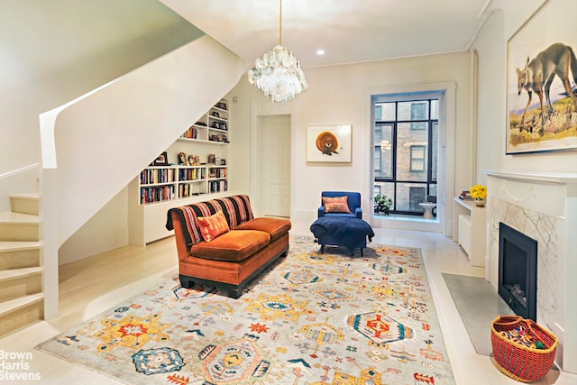 living area featuring a premium fireplace, built in features, a chandelier, and light hardwood / wood-style floors