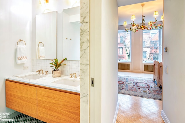 bathroom featuring double vanity, an inviting chandelier, a sink, and decorative backsplash