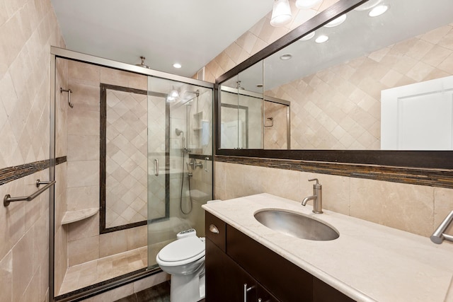 bathroom with toilet, tile walls, a shower stall, and vanity