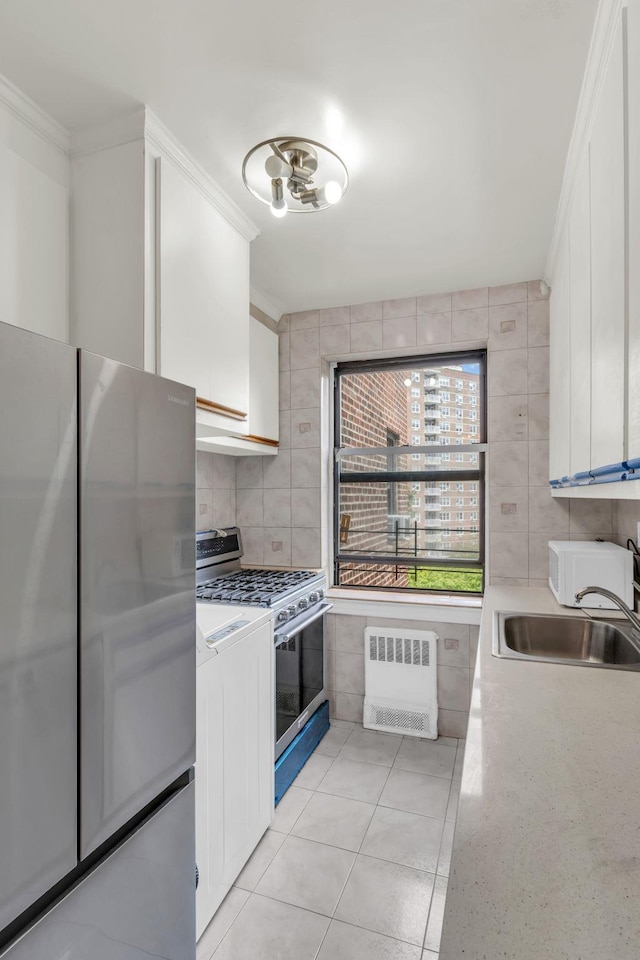 kitchen featuring radiator heating unit, a sink, stainless steel appliances, light countertops, and crown molding