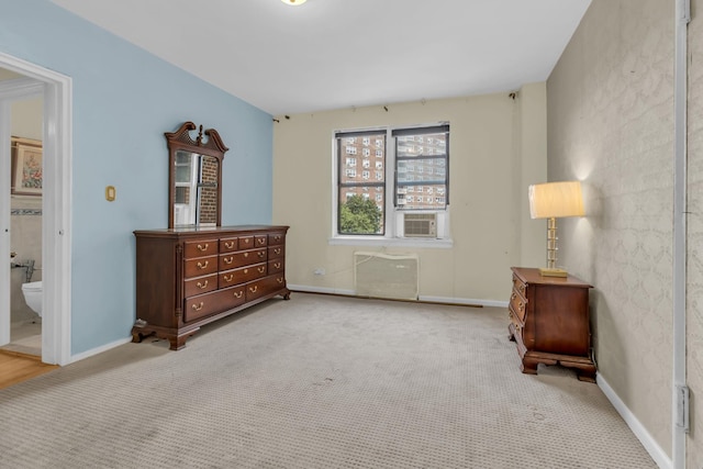 carpeted bedroom featuring cooling unit, ensuite bath, and baseboards