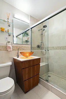 bathroom featuring toilet, vanity, tile patterned flooring, tile walls, and a shower with shower door