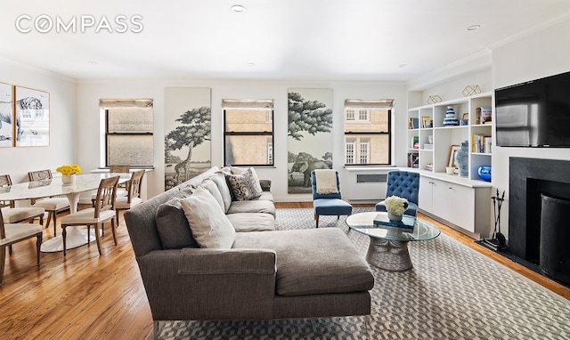 living room featuring light wood-style flooring, a fireplace, and ornamental molding