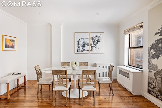 dining area featuring hardwood / wood-style flooring, radiator, and crown molding