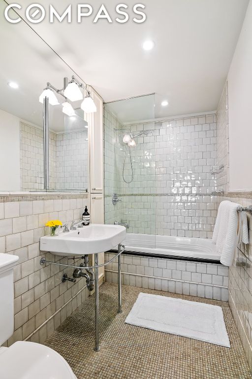 full bathroom featuring combined bath / shower with glass door, tile walls, toilet, and tile patterned flooring