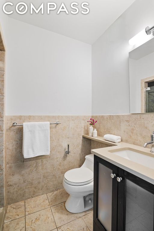 bathroom featuring toilet, tile walls, tile patterned floors, and vanity