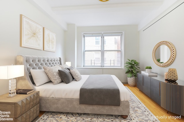 bedroom with light hardwood / wood-style floors and beam ceiling