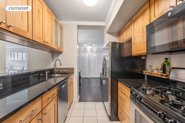 kitchen with dark stone countertops, appliances with stainless steel finishes, sink, light tile patterned floors, and crown molding