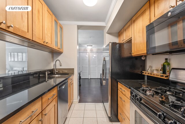 kitchen with glass insert cabinets, appliances with stainless steel finishes, dark stone countertops, ornamental molding, and a sink