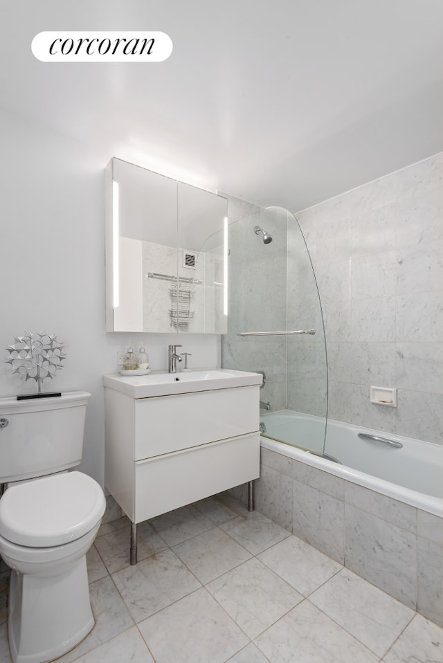 bathroom with tiled shower / bath combo, toilet, marble finish floor, and vanity