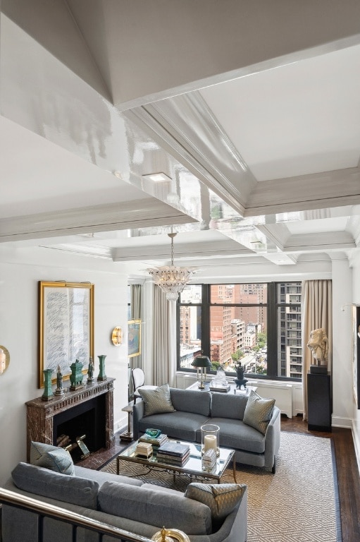 living room featuring an inviting chandelier, crown molding, a fireplace, and hardwood / wood-style flooring