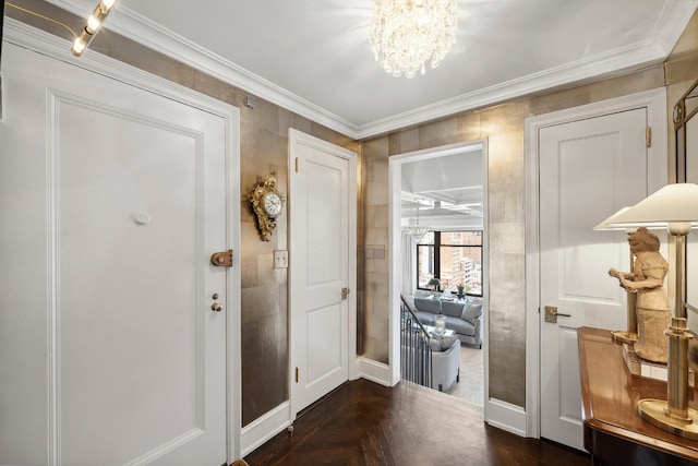 entryway with ornamental molding, dark parquet flooring, and a chandelier